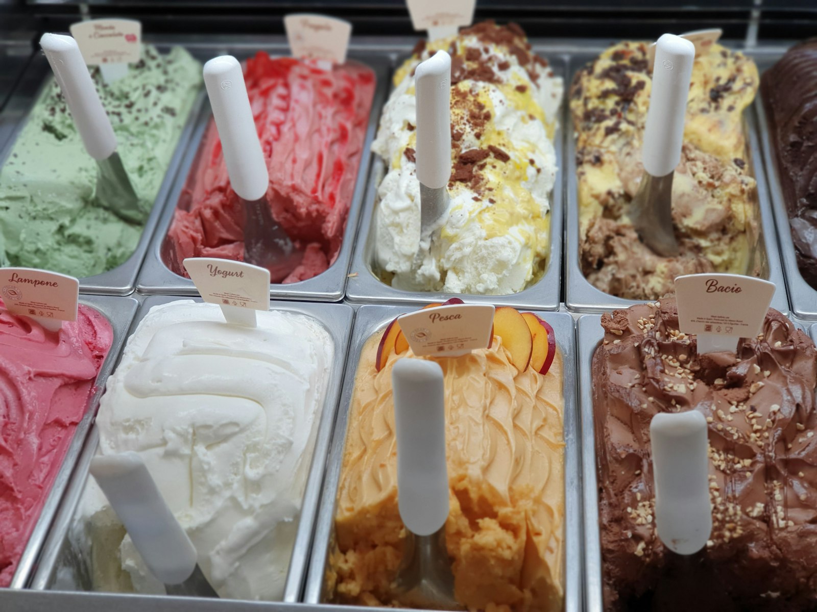 A display counter filled with tubs of freshly made Italian gelato in many colours and flavours
